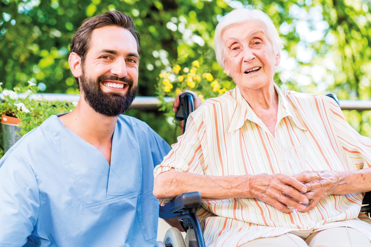 ein Pfleger mit einer älteren Dame im Rollstuhl